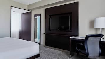 Een hotelkamer met een bed, bureau, stoel, televisie en lamp.