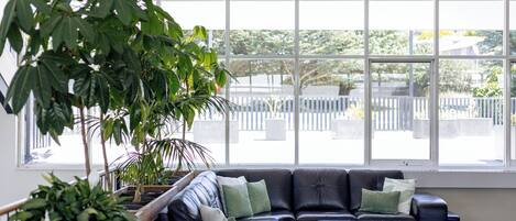 Un interior moderno con un sofá modular, ventanas amplias y plantas de interior.