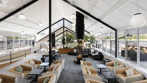 Un espacio interior amplio con diversas disposiciones de asientos, un hogar central y ventanas grandes que ofrecen vistas al exterior.