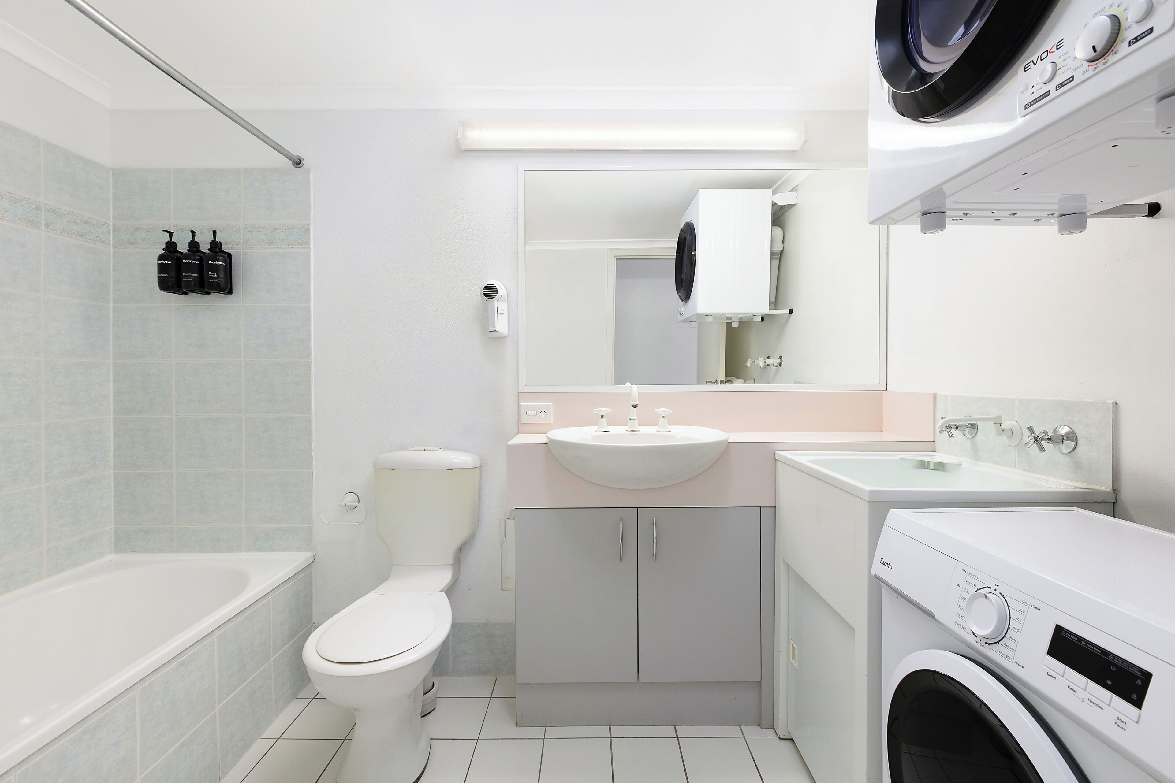Un baño moderno con bañera, inodoro, lavamanos y lavadora.