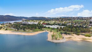 Vista aérea de una zona costera con un complejo arquitectónico grande, una playa y colinas circundantes.