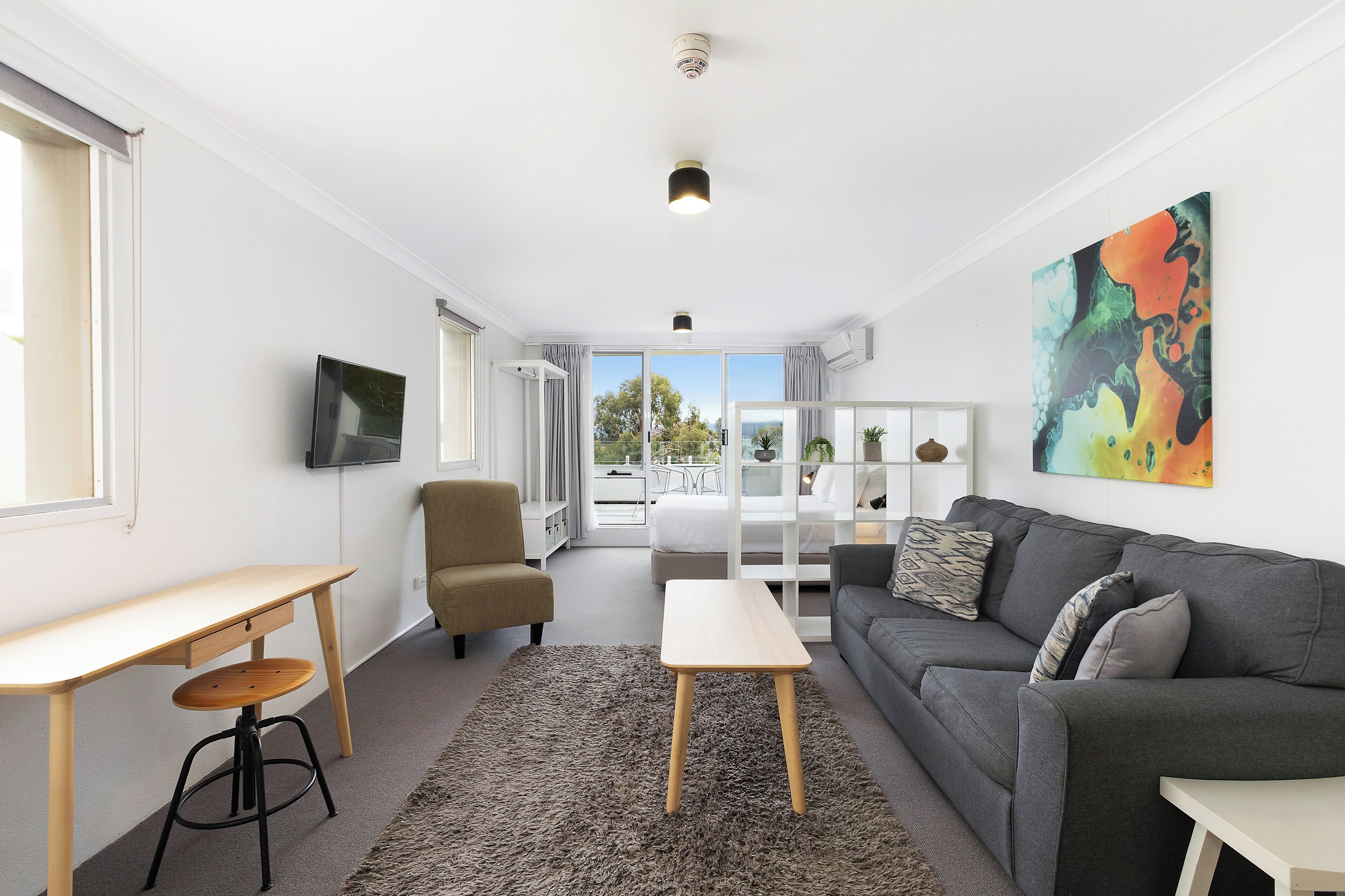 Een moderne woonkamer met een bank, een klein tafeltje, een stoel en een groot raam.