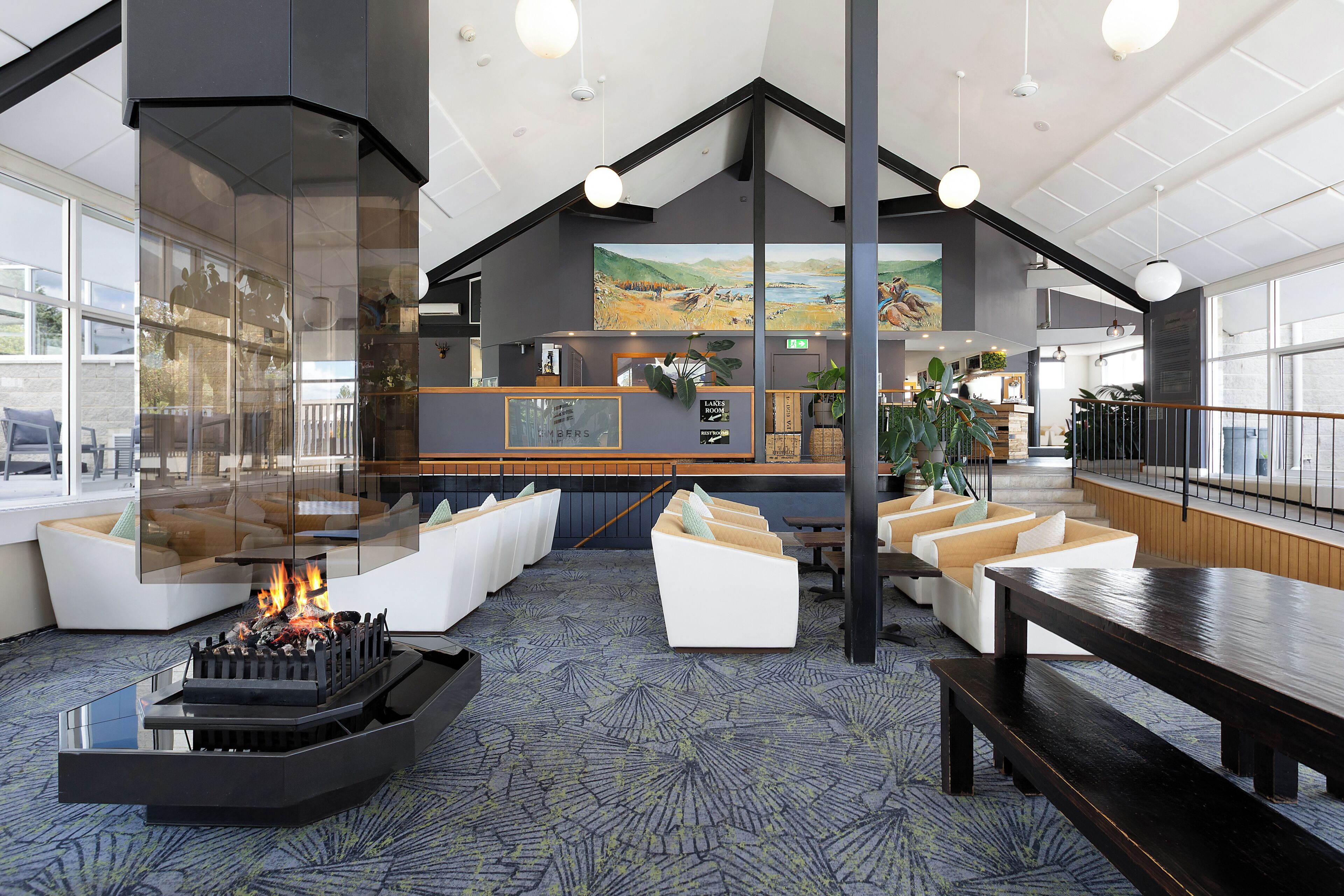 A modern lobby with a fireplace, seating areas, and a view of the kitchen.