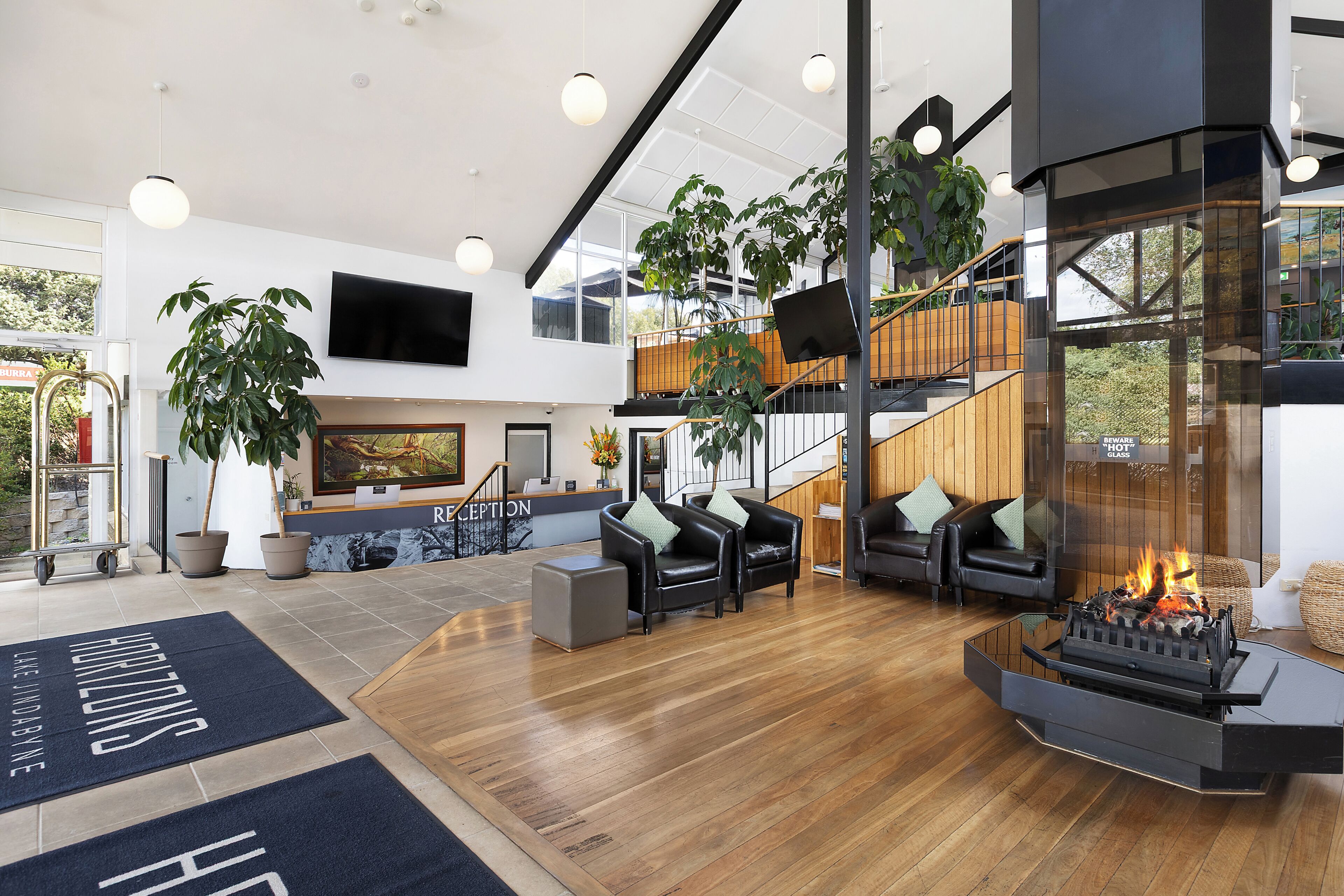 A modern reception area with a fireplace, seating, and a staircase leading to an upper level.