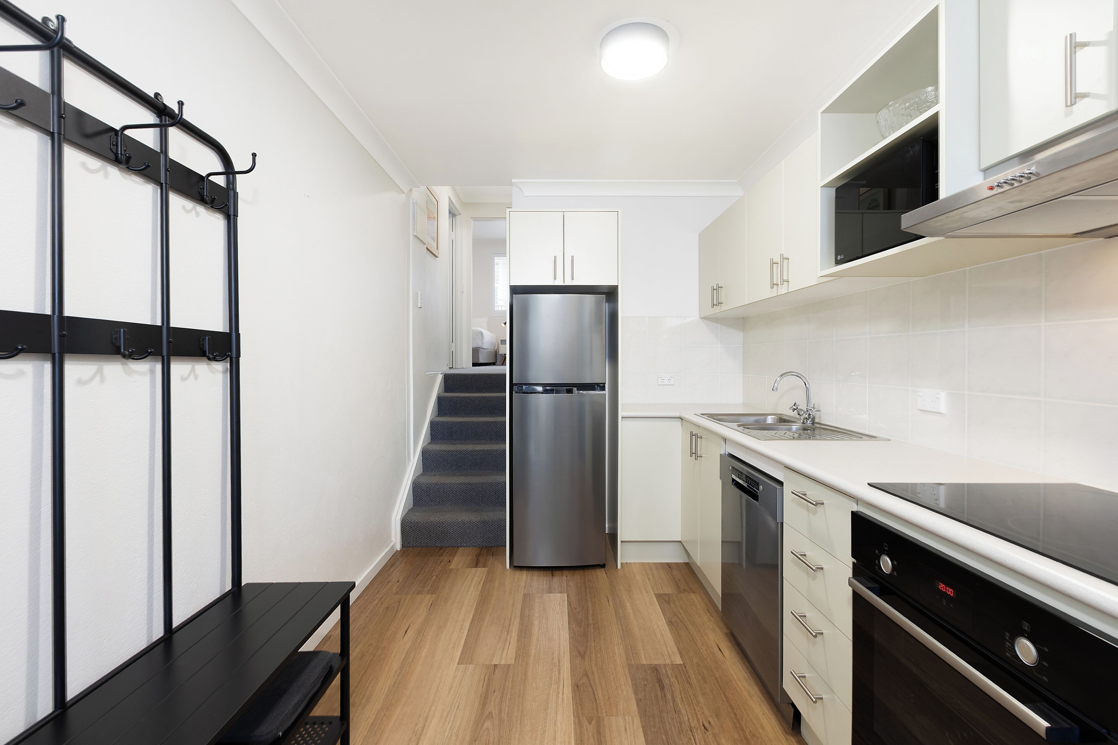 A modern kitchen with a stainless steel refrigerator, a dishwasher, and a black countertop.