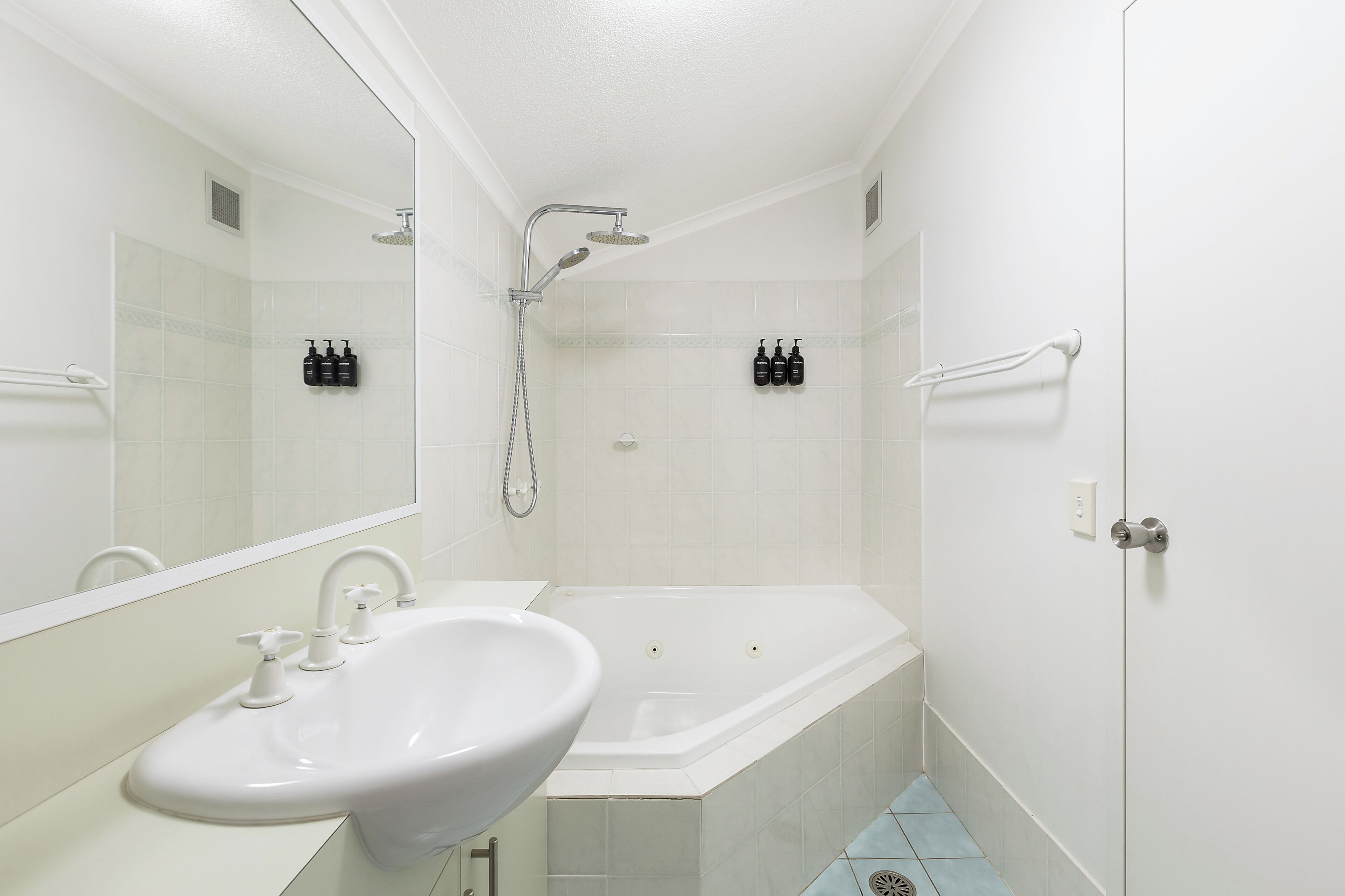 A bathroom with a sink, mirror, shower, and bathtub.