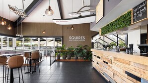 Un bar y jardín de cerveza con mostrador de madera, taburetes y plantas en macetas.