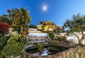 A garden with a stone bridge, water features, and various plants.