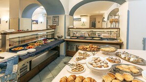 Ein reichhaltiges Buffet mit verschiedenen Speisen und eine Sitzgelegenheit mit Tischen und Stühlen.