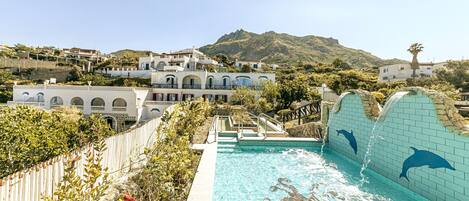 A swimming pool with dolphin murals, surrounded by a wooden fence and lush greenery.