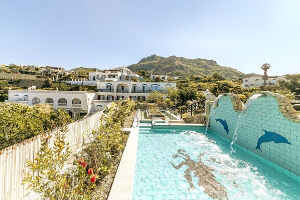 A swimming pool with dolphin murals, surrounded by a wooden fence and lush greenery.