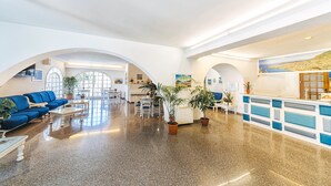 Eine großzügige Lobby mit Empfangsschalter, Sitzgelegenheiten und Rundbogenöffnungen.