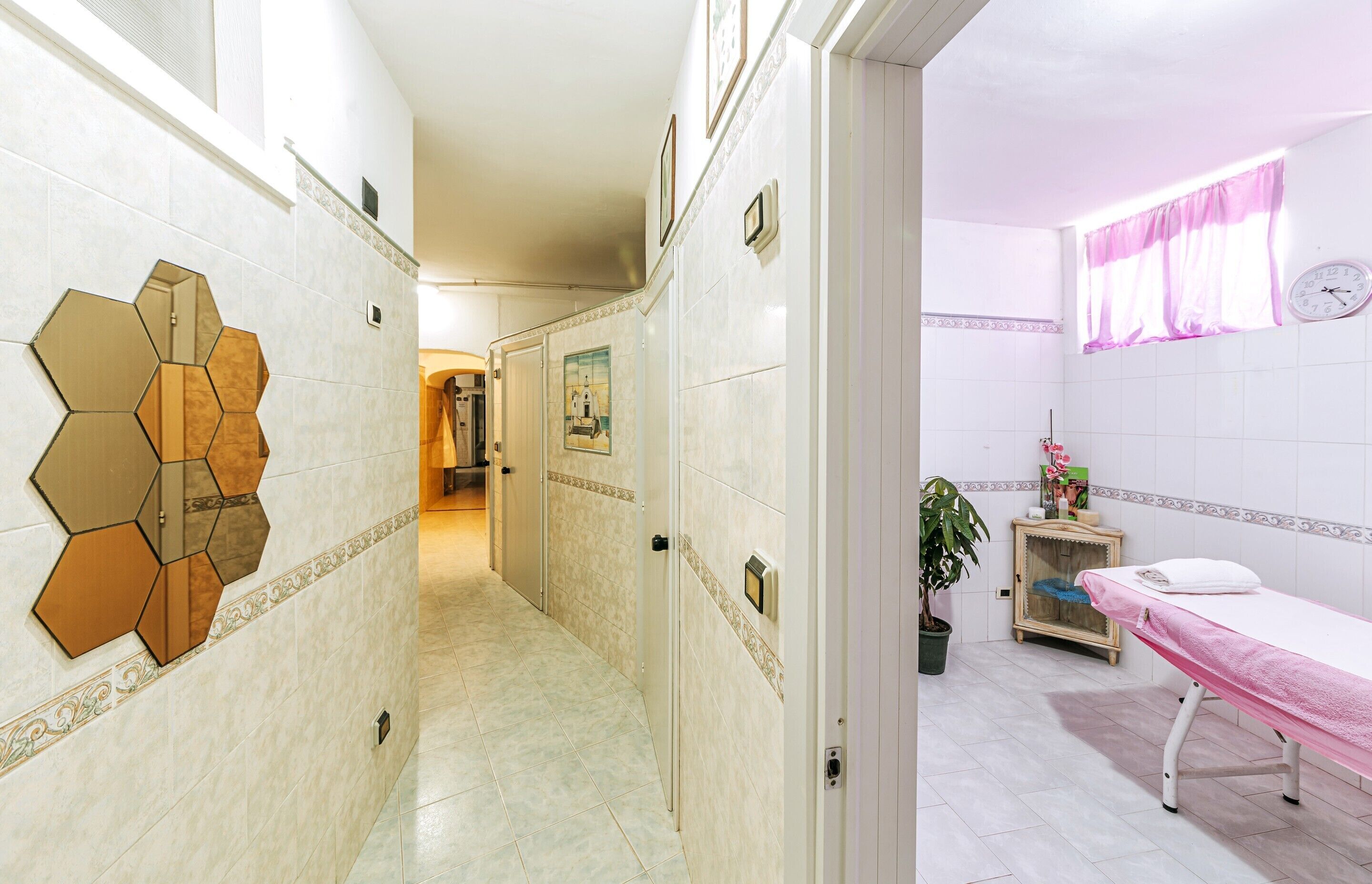 A hallway with hexagonal mirrors and a reception area with a clock.