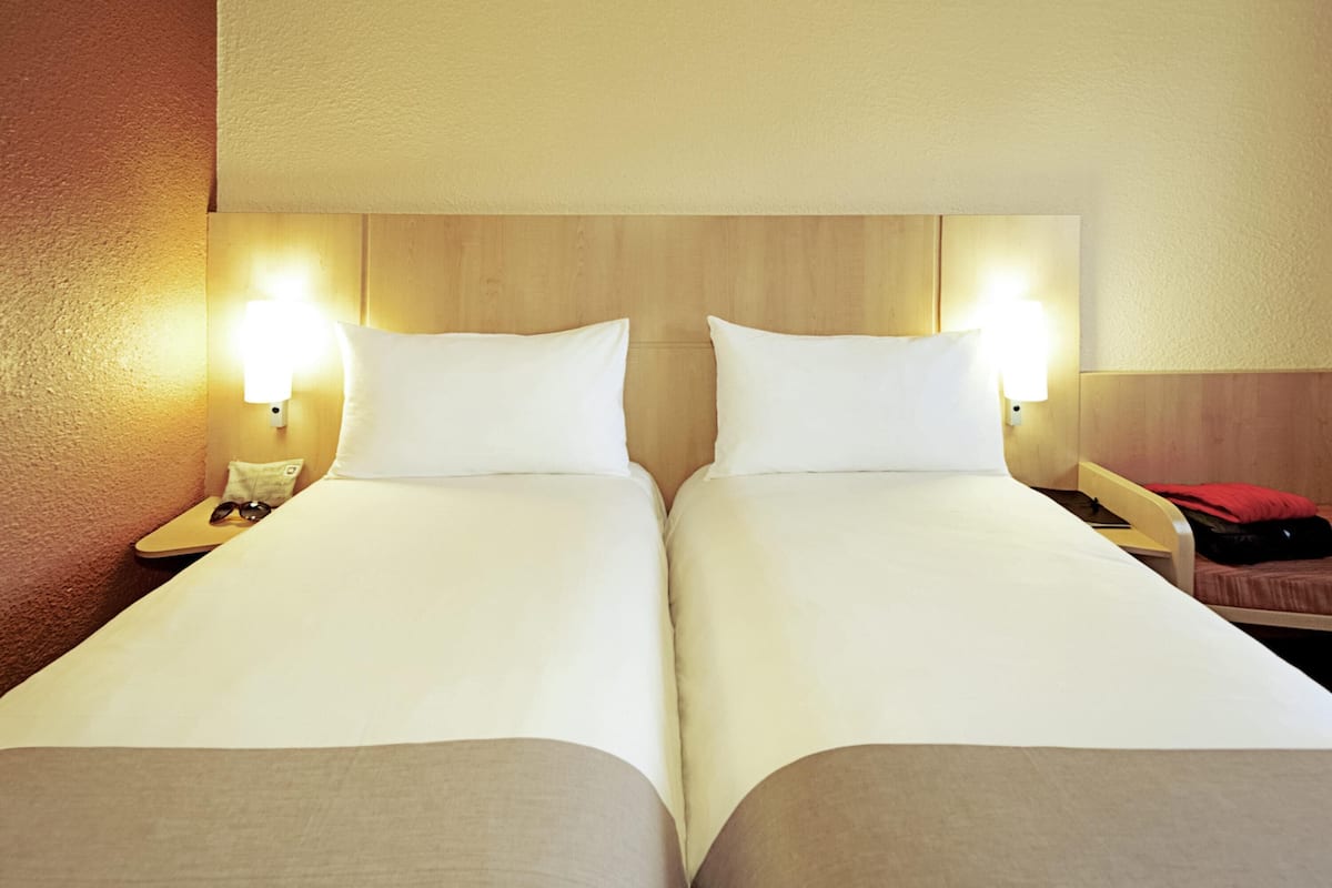 A double room with two beds, bedside lamps, and a wooden headboard.