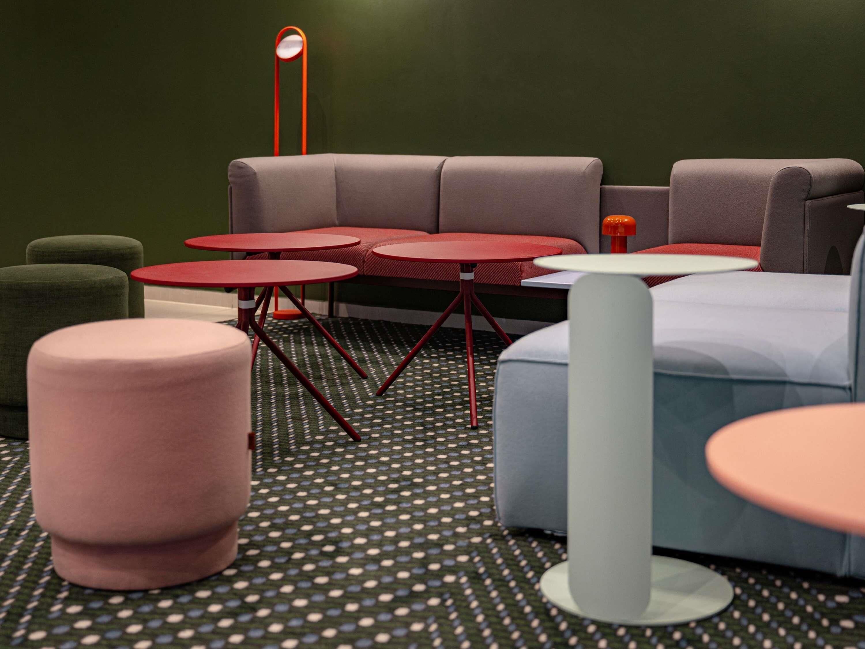 Un espace de détente moderne comprenant un canapé, plusieurs tables rondes et un sol à motifs.