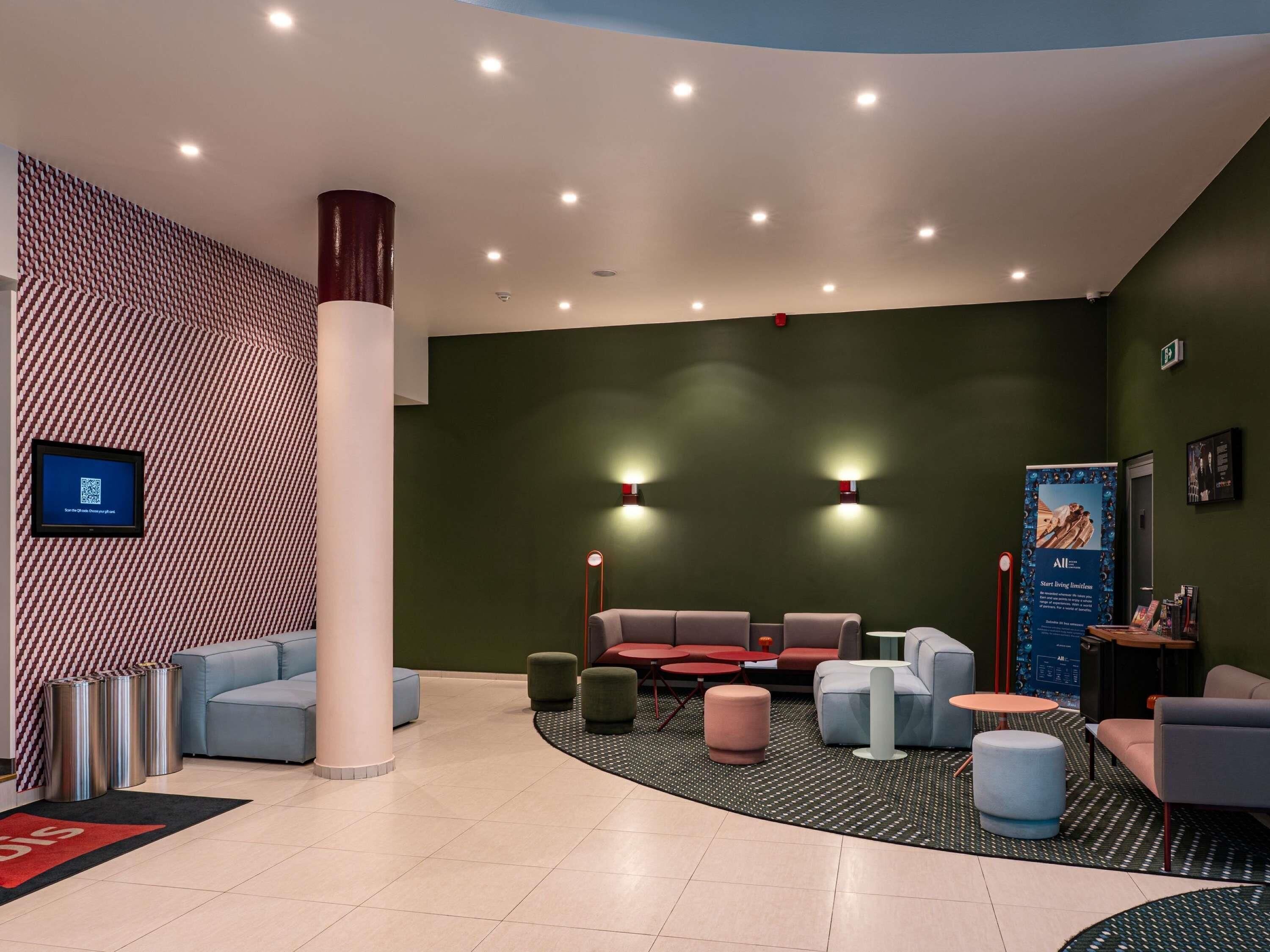 Un hall d’entrée moderne doté d’un espace salon aux lignes courbes, d’un écran numérique et d’un comptoir d’accueil.
