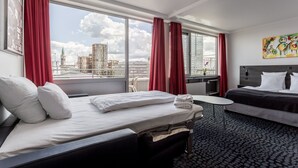 A hotel room with a bed, a small table, and a view of the cityscape. - ProfilHotels Mercur (Copenhagen)