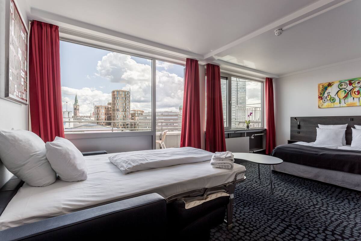 Una camera d'albergo con un letto, un tavolino e vista sulla città.