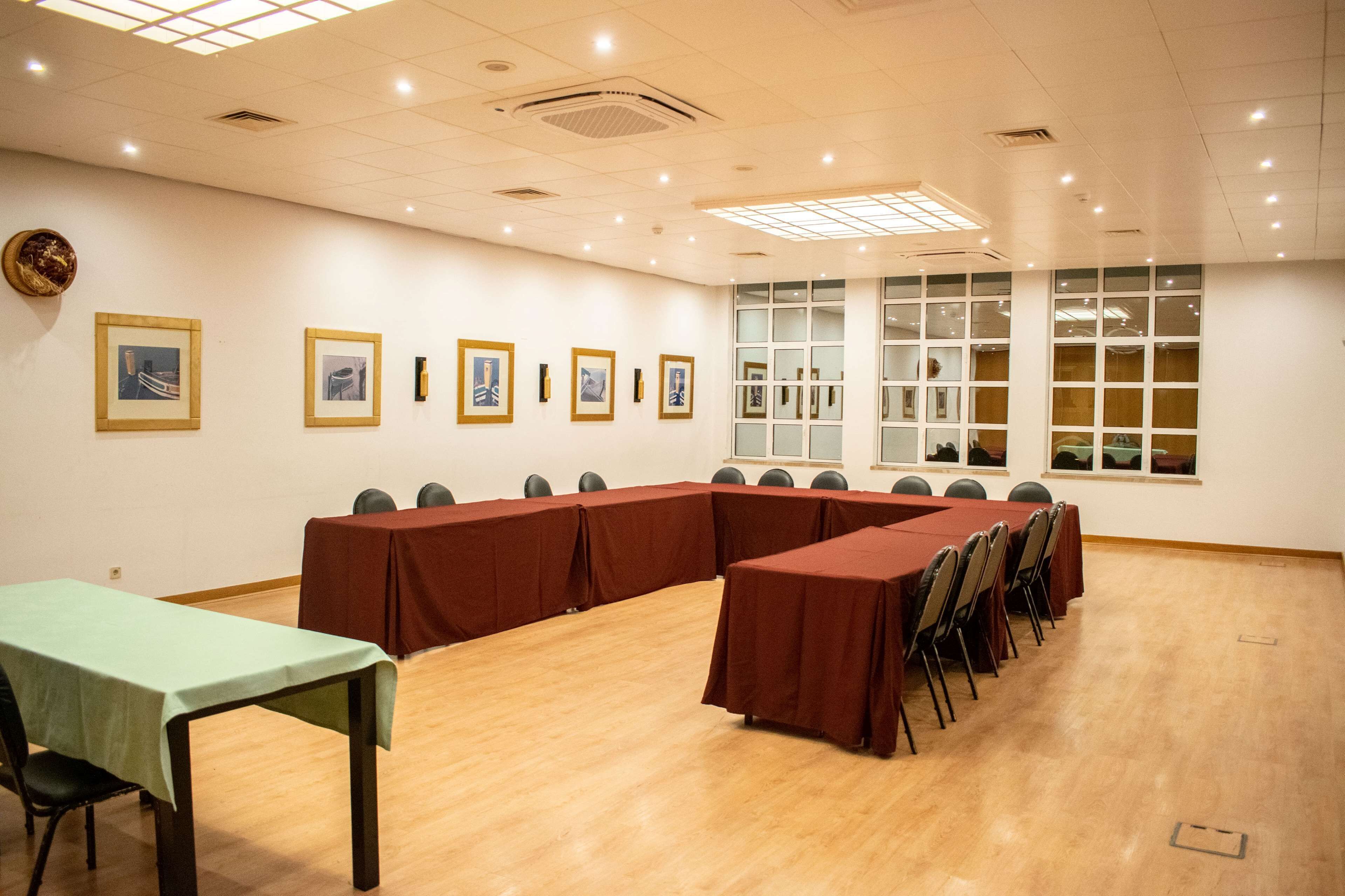 Un salón de conferencias con una larga mesa, sillas y cuadros en la pared.