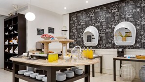 Une cuisine moderne avec un plan de travail en marbre, de l’argenterie noire et blanche, et un mur décoré sur le thème du café.