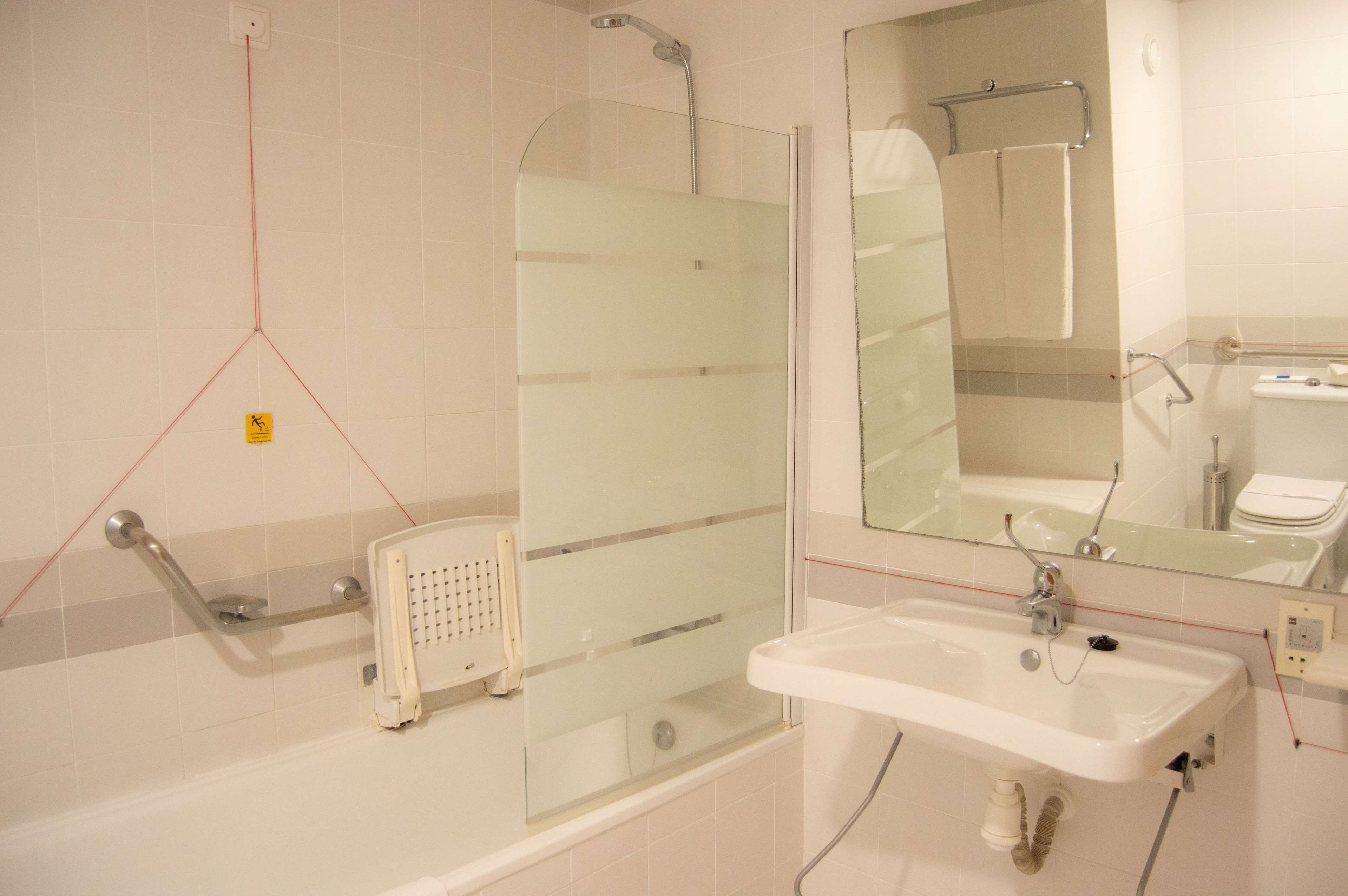 A bathroom with a glass-enclosed shower, a white sink, and a mirror.