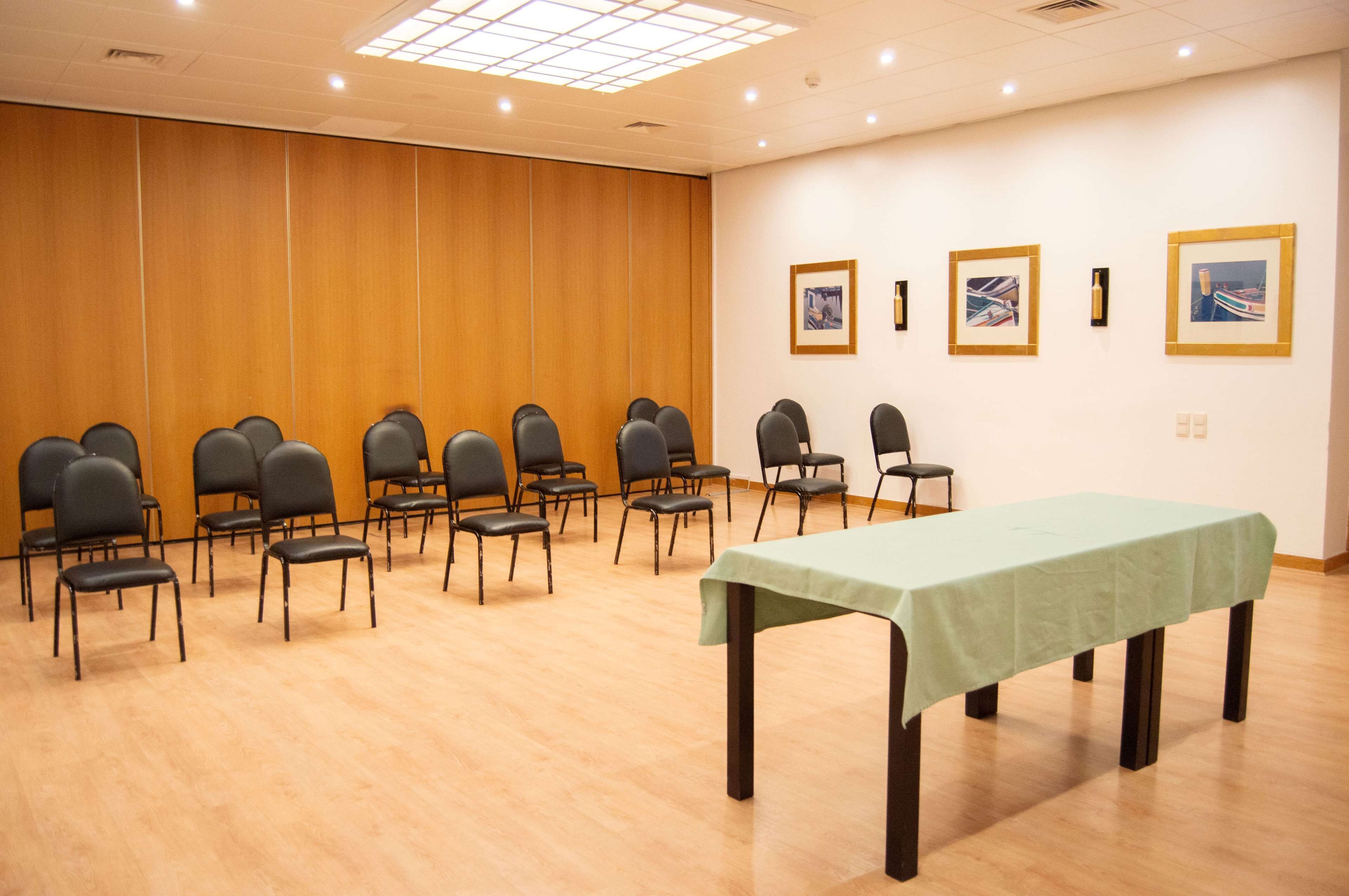A conference room with rows of chairs, a table, and framed pictures on the wall.