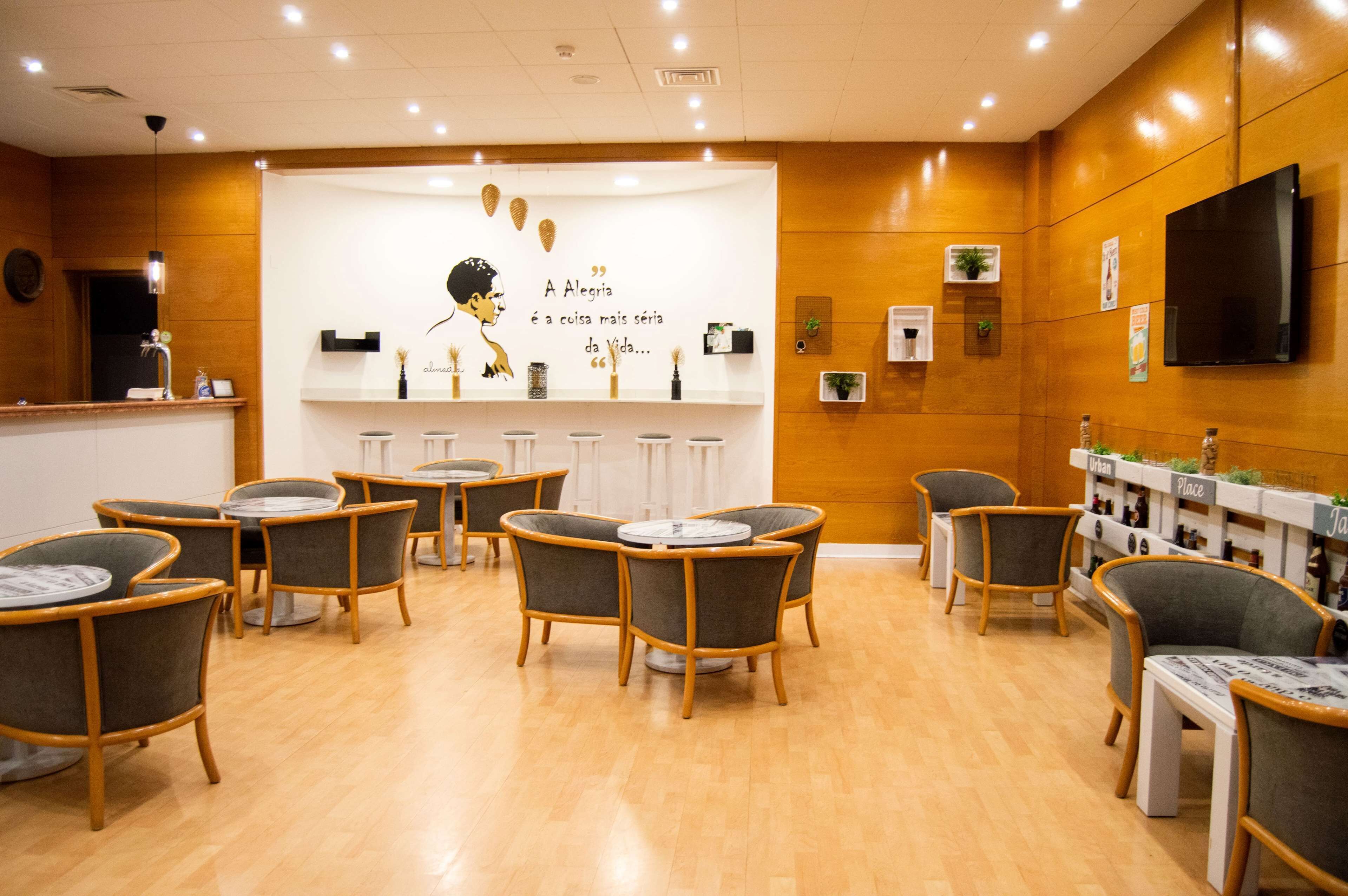 A modern interior with round tables and chairs, a reception desk, and a wall with a quote and decorative items.