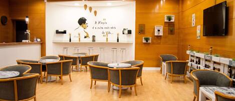 A modern interior with round tables and chairs, a reception desk, and a wall with a quote and decorative items.