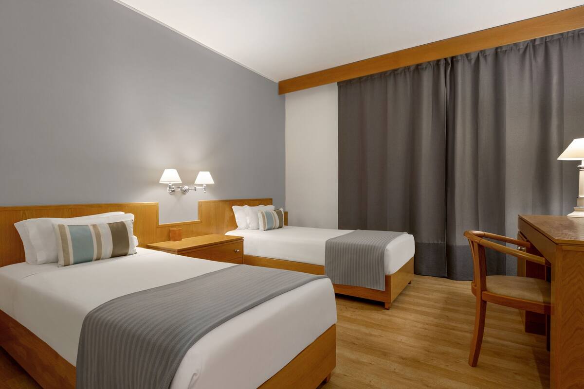 Habitación de hotel con dos camas, un escritorio y una silla.