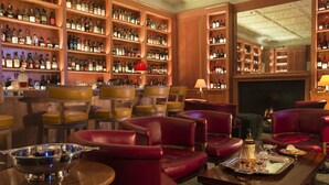 Un área de bar con sillones de cuero, una chimenea y estantes llenos de botellas de licores.
