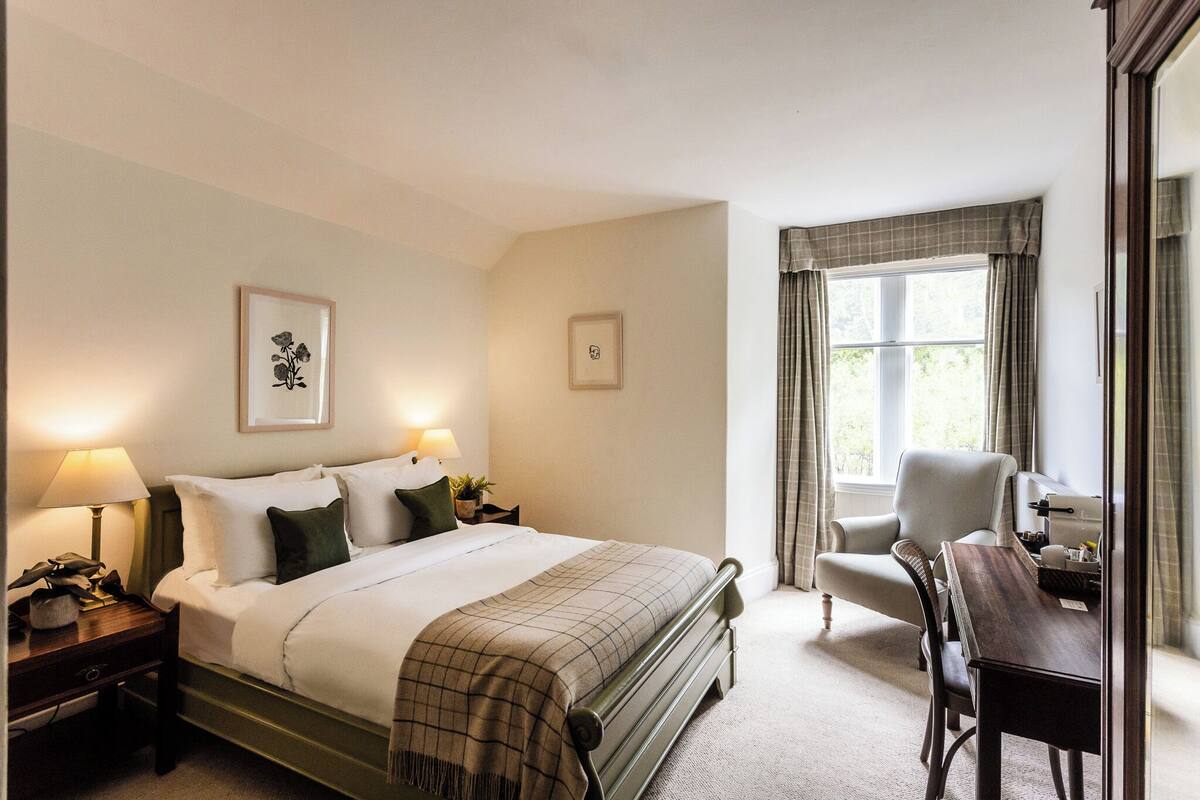 Ein Hotelzimmer mit Bett, Nachttischen, einem Schreibtisch und einem Stuhl.