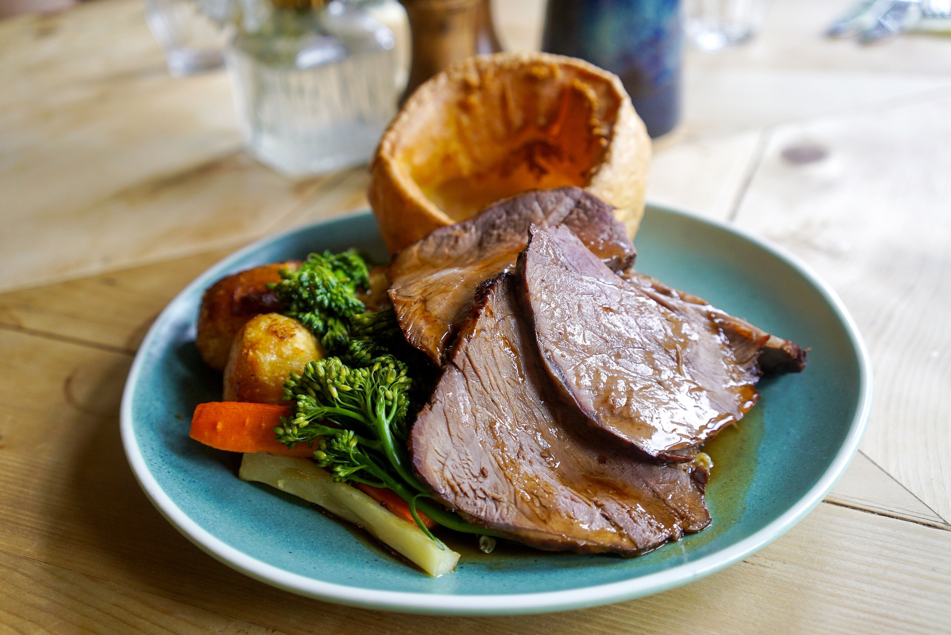 A plate of food with roast beef, Yorkshire pudding, and vegetables.