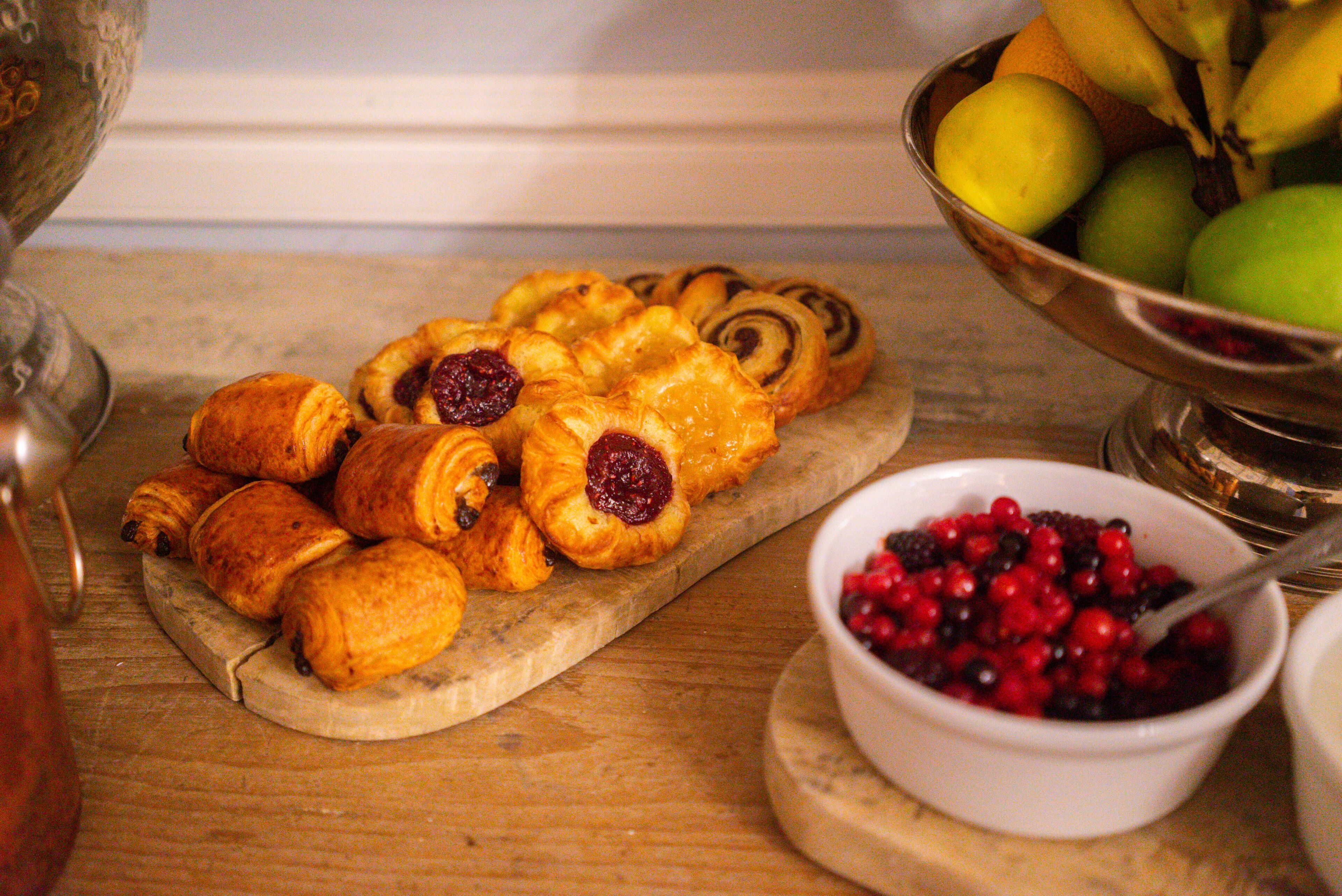 A wooden board with pastries and a bowl of berries.