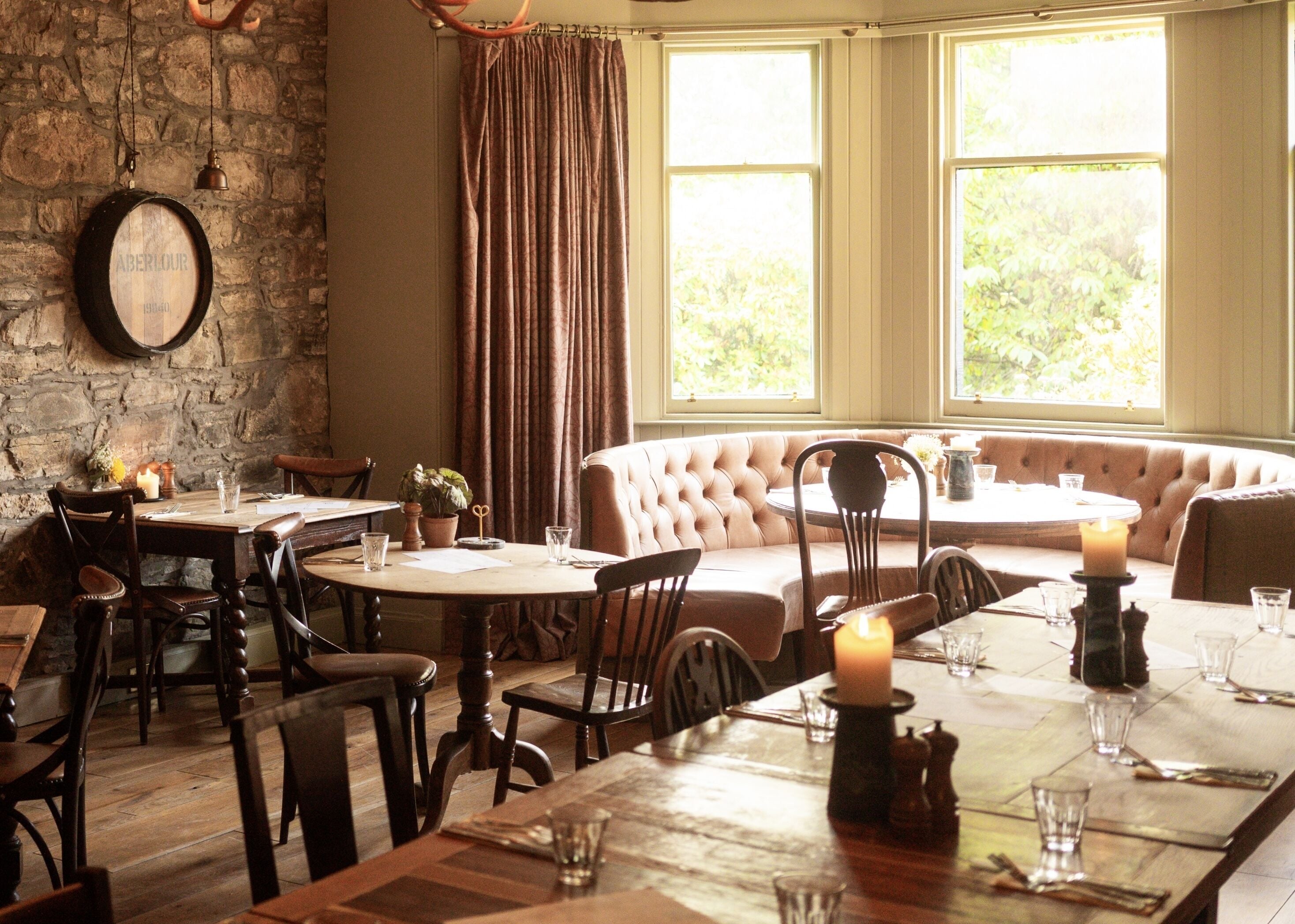 A dining area with a stone wall, wooden tables, and a cushioned bench.