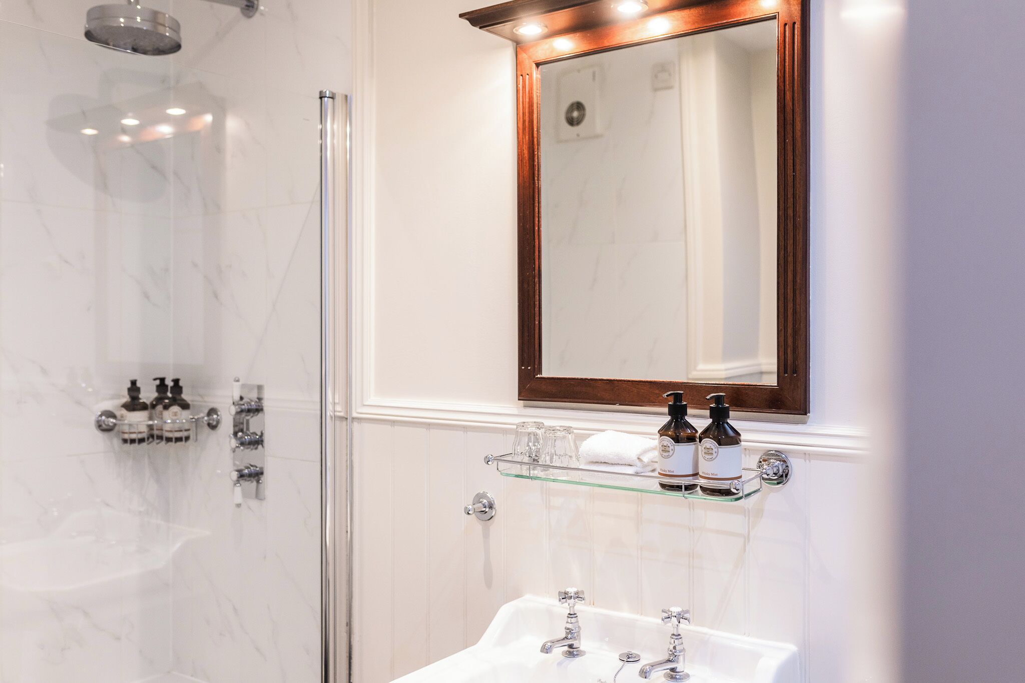 Un baño moderno con cabina de ducha de vidrio, tocador con espejo y lavabo.