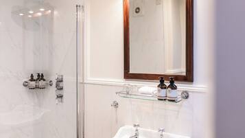 Un baño moderno con cabina de ducha de vidrio, tocador con espejo y lavabo.