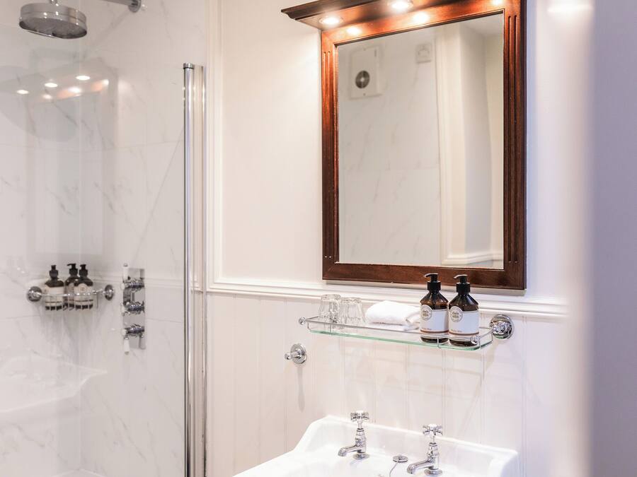 Un baño moderno con cabina de ducha de vidrio, tocador con espejo y lavabo.