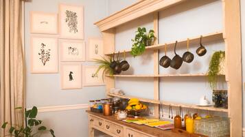 A kitchen with wooden shelves, framed botanical prints, and various kitchen utensils.
