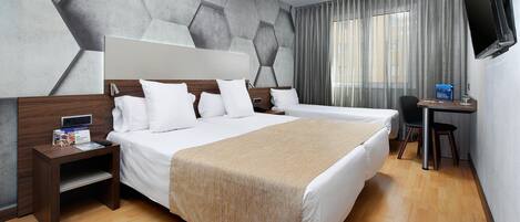 Habitación de hotel con una cama grande, un escritorio, una silla, un televisor y una ventana con cortinas.