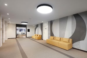 Un vestíbulo moderno con dos sofás, un mostrador de recepción y una pared grande con diseños abstractos.