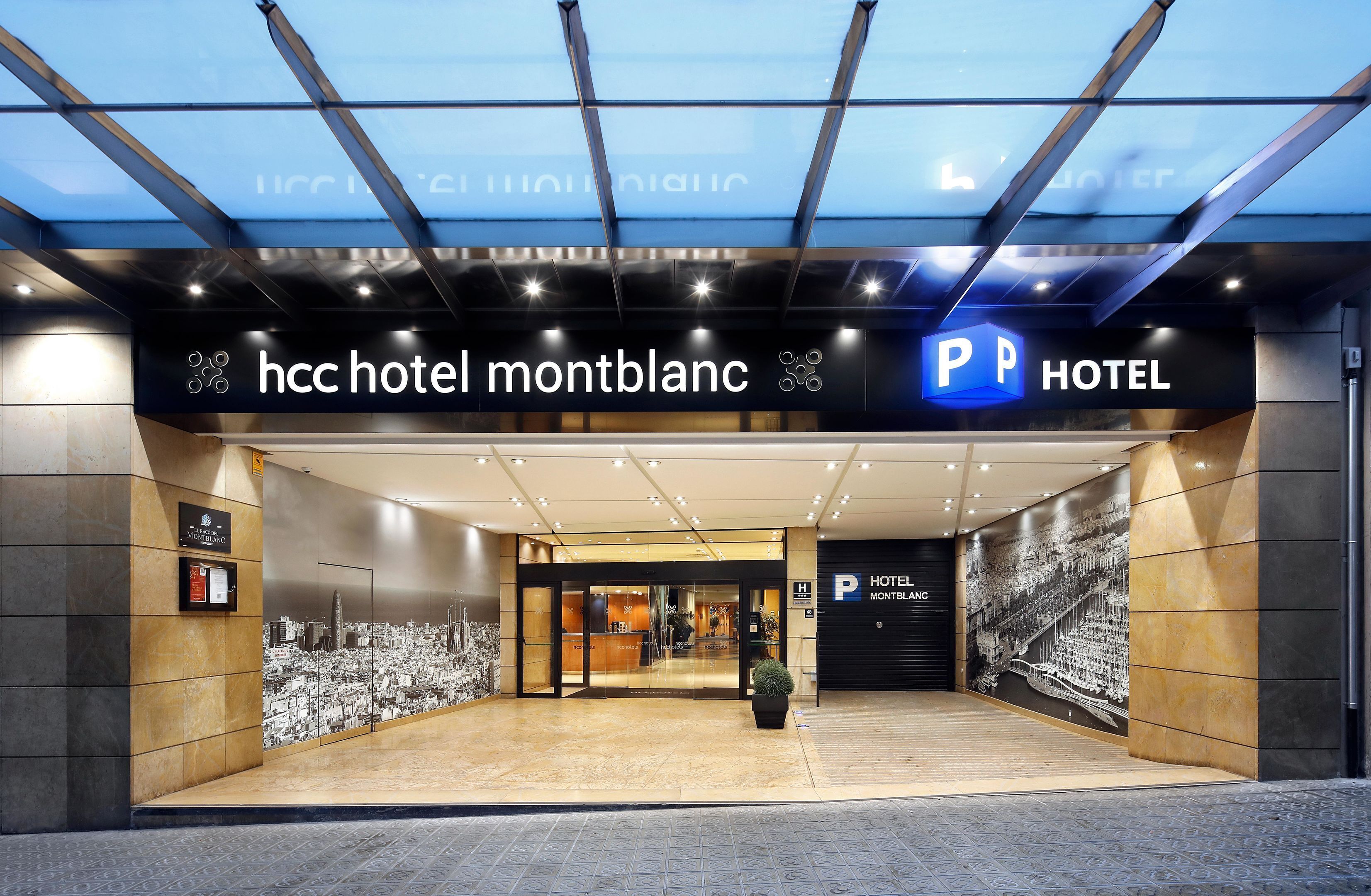 La entrada del HCC Hotel Montblanc, con un diseño moderno, un toldo de cristal y un cartel de estacionamiento.
