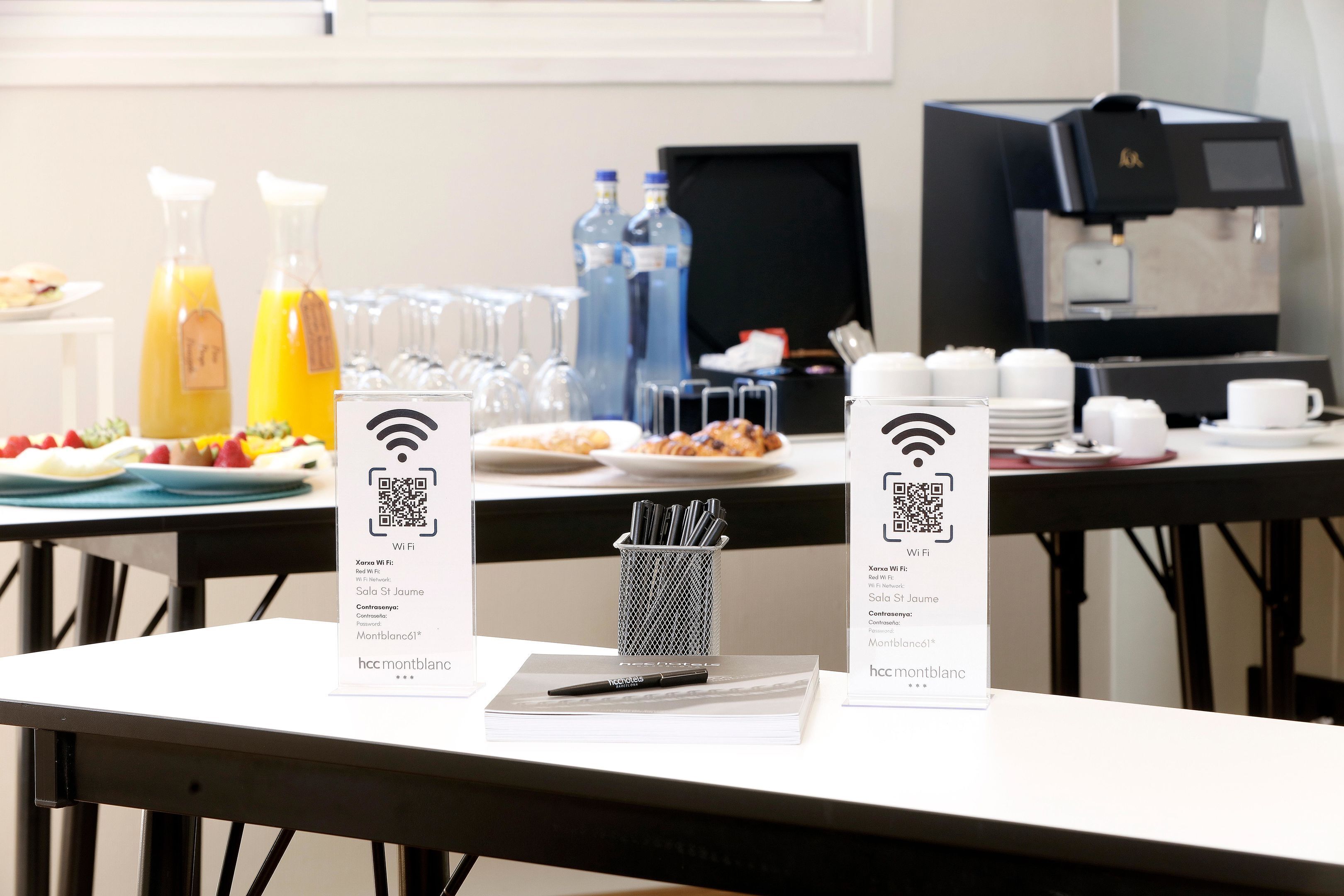 A breakfast setup with a coffee machine, water bottles, and a QR code sign for Wi-Fi access.