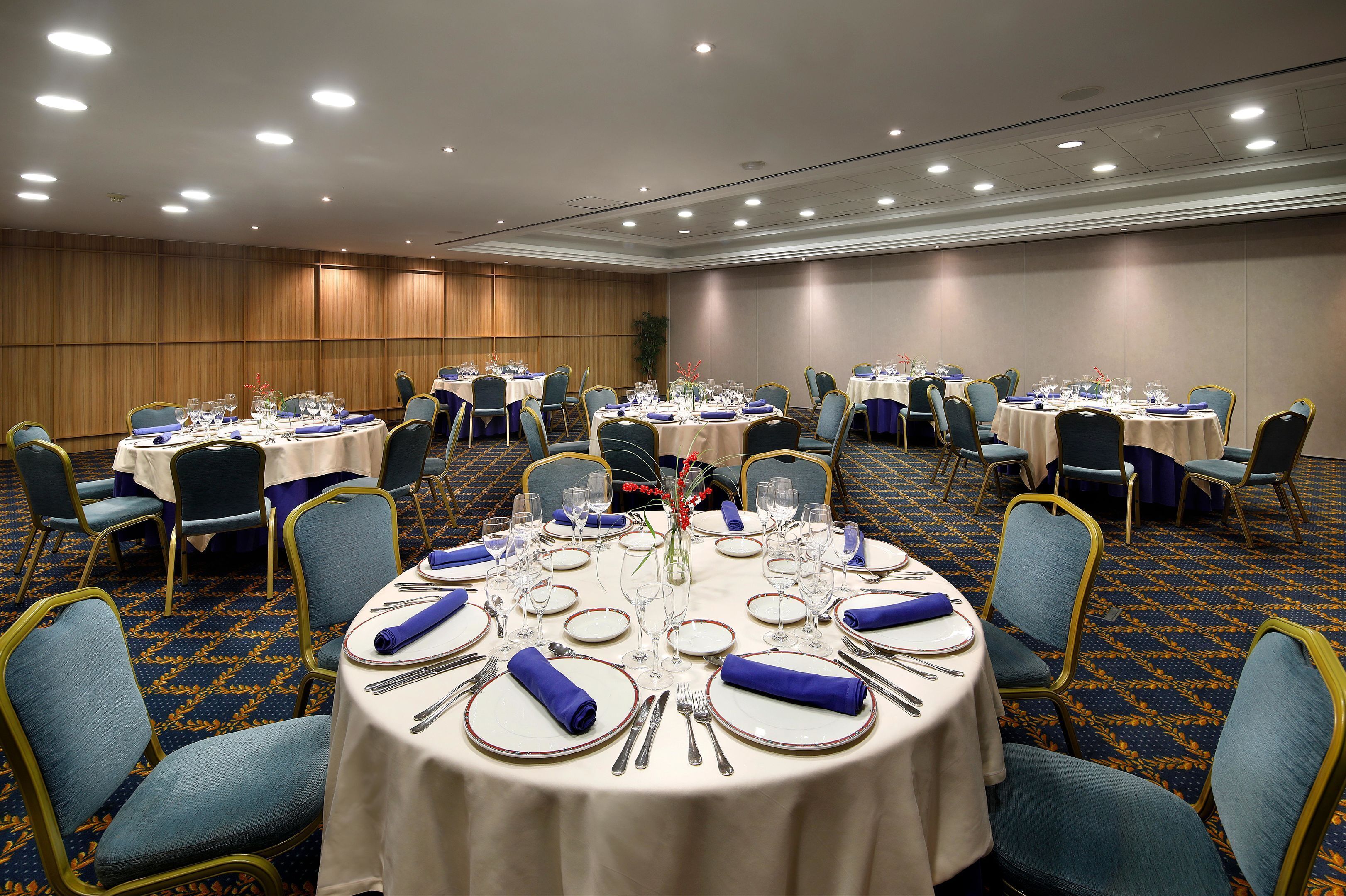 A conference room with round tables, chairs, and a carpeted floor.