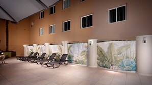 Un área de spa con sillones reclinables, suelo de baldosas y un mural de plantas tropicales.