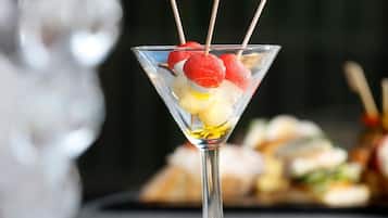 A martini glass with a cocktail garnish on a reflective surface.