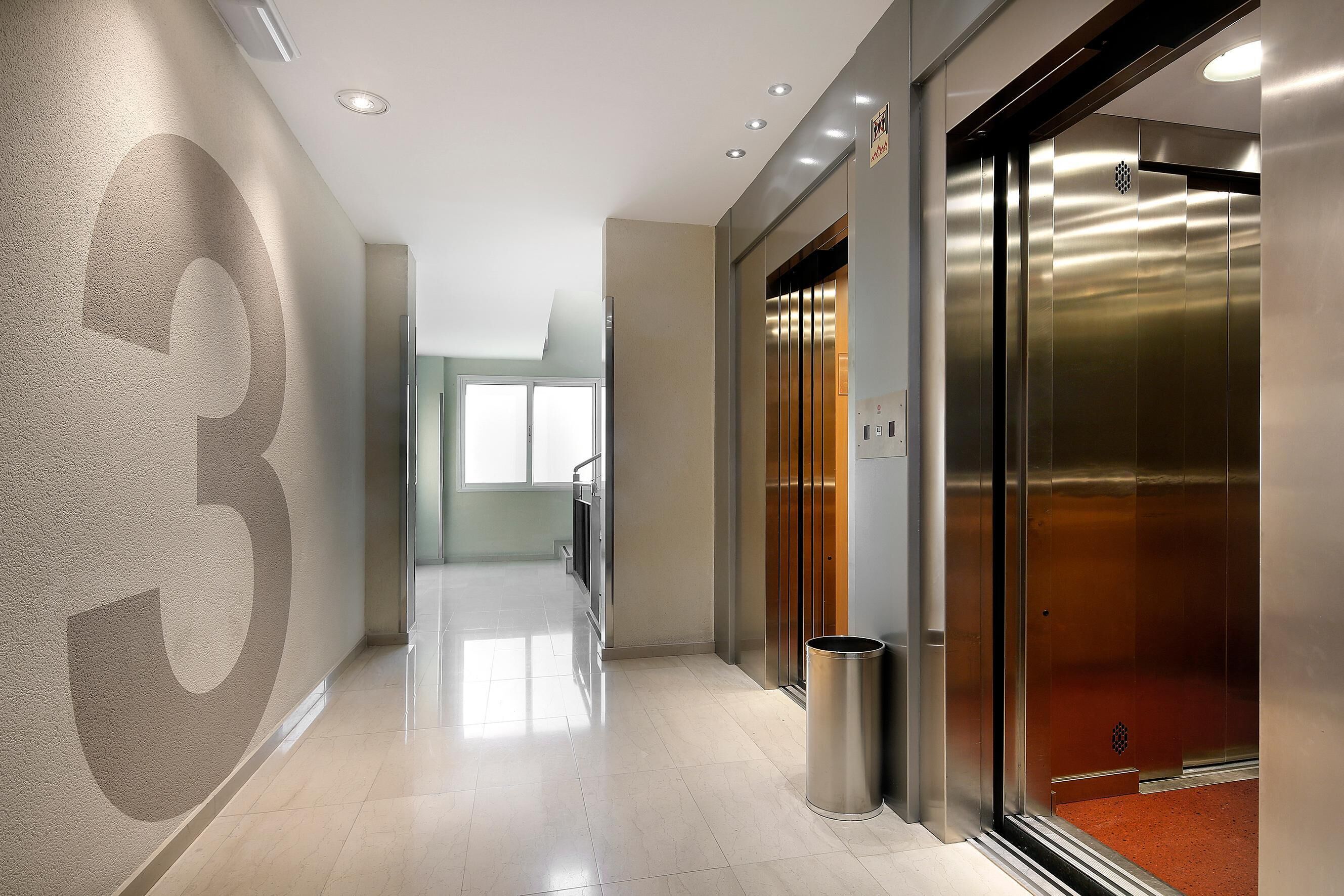 A modern hallway with a large number '3' on the wall, a trash bin, and an elevator.