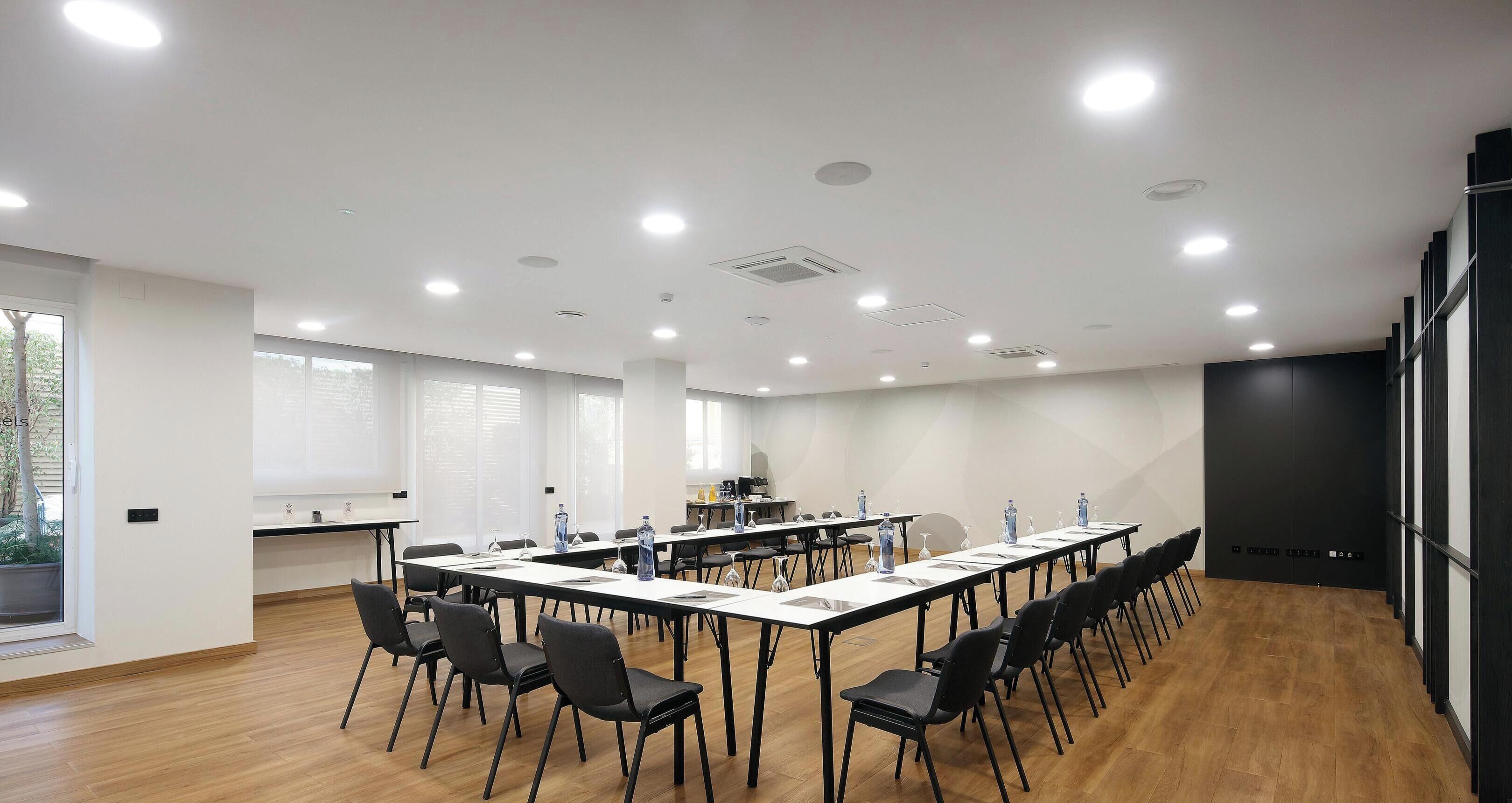 A conference room with a long table, chairs, and a kitchenette area.