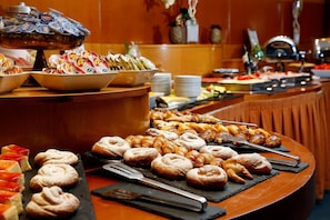 Un bufé con diversas opciones de pasteles y postres, incluyendo croissants y otras delicias horneadas.