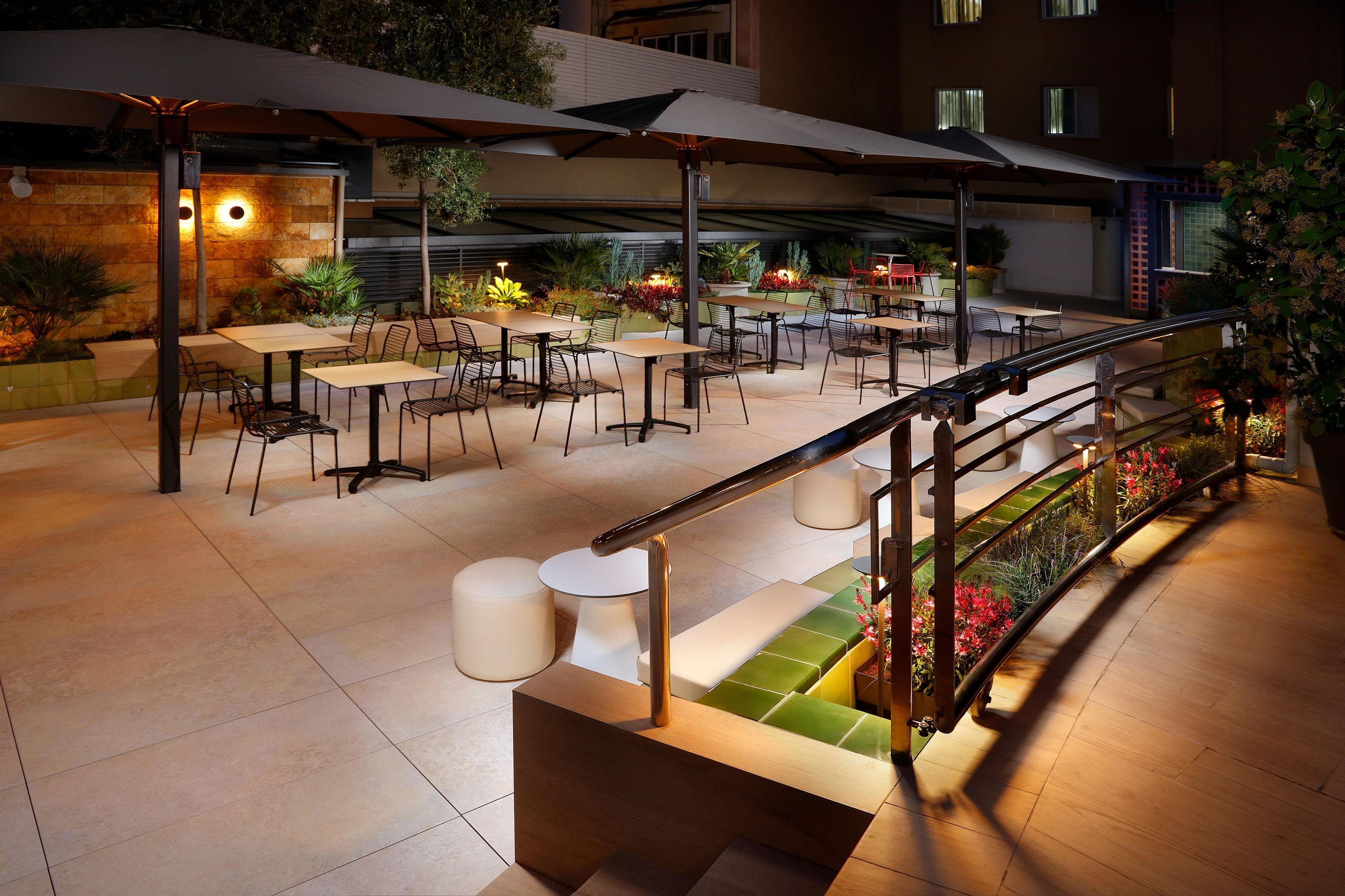 An outdoor patio area with tables and chairs, a staircase, and a railing.