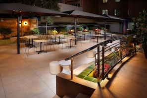 An outdoor patio area with tables and chairs, a staircase, and a railing. - Hotel HCC MontBlanc (Barcelona)